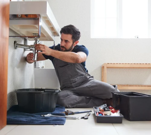male-plumber-working-to-fix-leaking-sink-in-home-bathroom